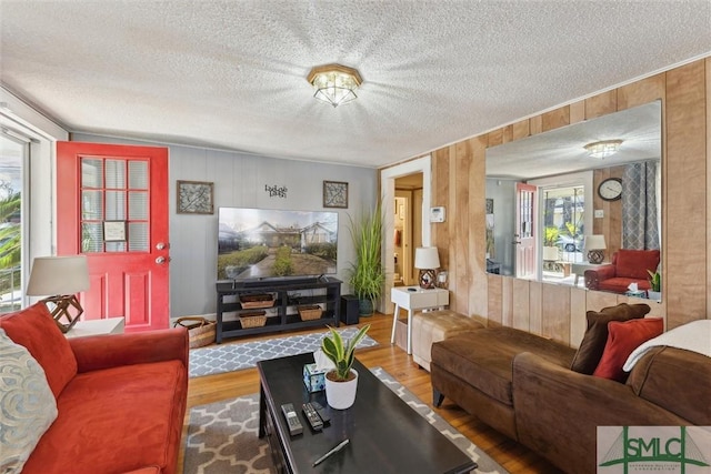 living room featuring a textured ceiling, hardwood / wood-style floors, and wooden walls