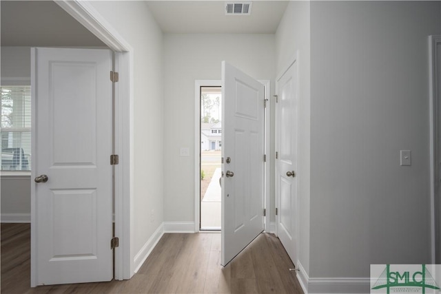 foyer with wood finished floors, visible vents, and baseboards