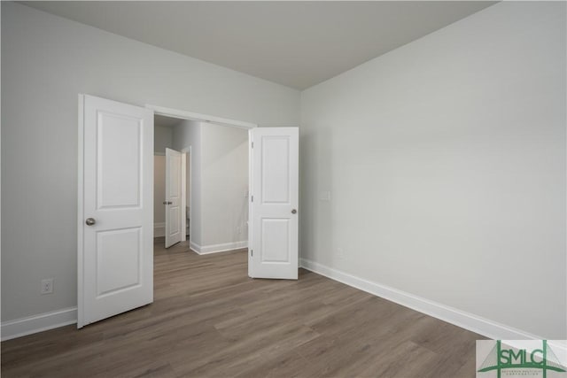 unfurnished bedroom with wood finished floors and baseboards