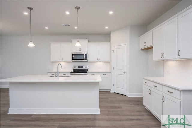 kitchen featuring a sink, wood finished floors, appliances with stainless steel finishes, and white cabinets