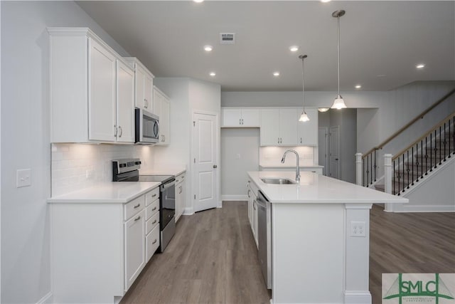 kitchen with a sink, backsplash, stainless steel appliances, light wood-style floors, and white cabinets