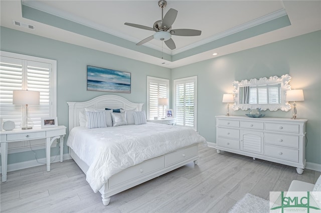 bedroom with light hardwood / wood-style floors, crown molding, and a raised ceiling