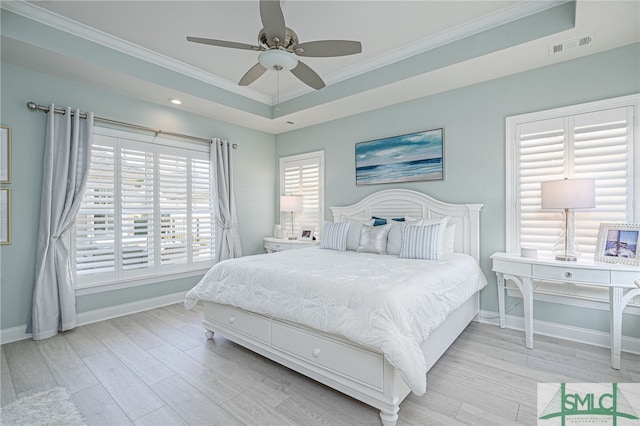 bedroom with a tray ceiling, light hardwood / wood-style flooring, crown molding, and ceiling fan