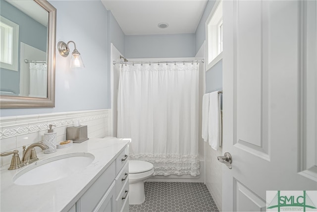 full bathroom with tile patterned flooring, toilet, tile walls, shower / bath combo with shower curtain, and vanity