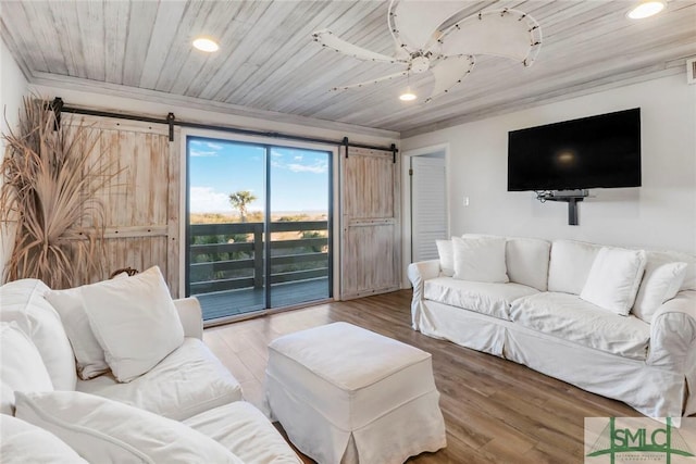 living room with hardwood / wood-style flooring, wood ceiling, a barn door, and ornamental molding