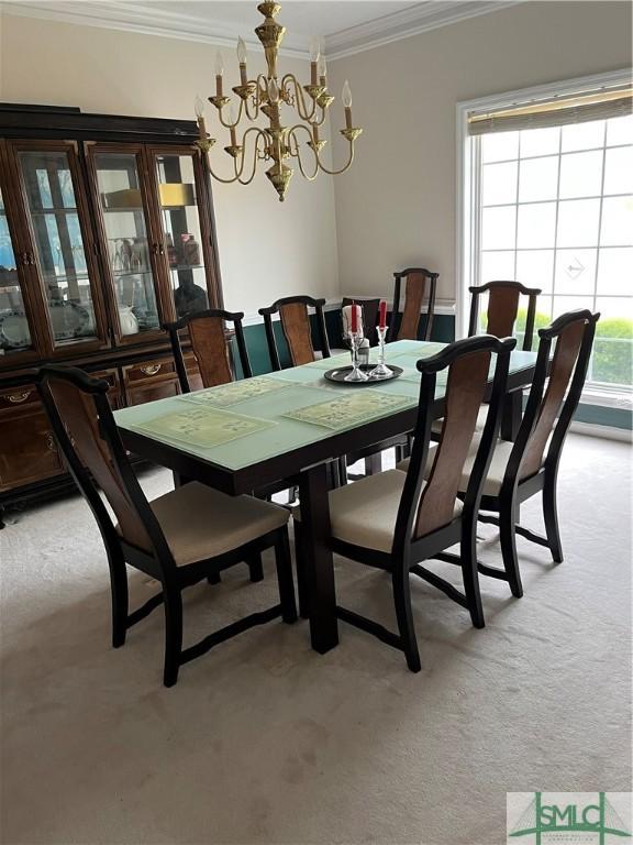 carpeted dining space featuring crown molding and an inviting chandelier