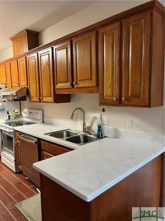 kitchen featuring dishwasher, light stone countertops, electric range, sink, and kitchen peninsula