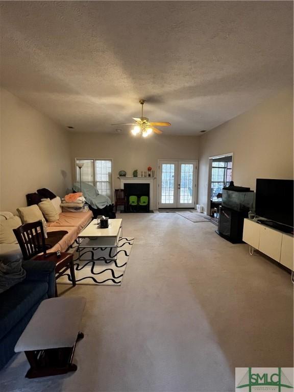 carpeted living room with french doors and a textured ceiling