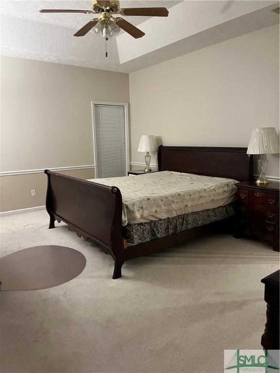 carpeted bedroom featuring ceiling fan and a textured ceiling