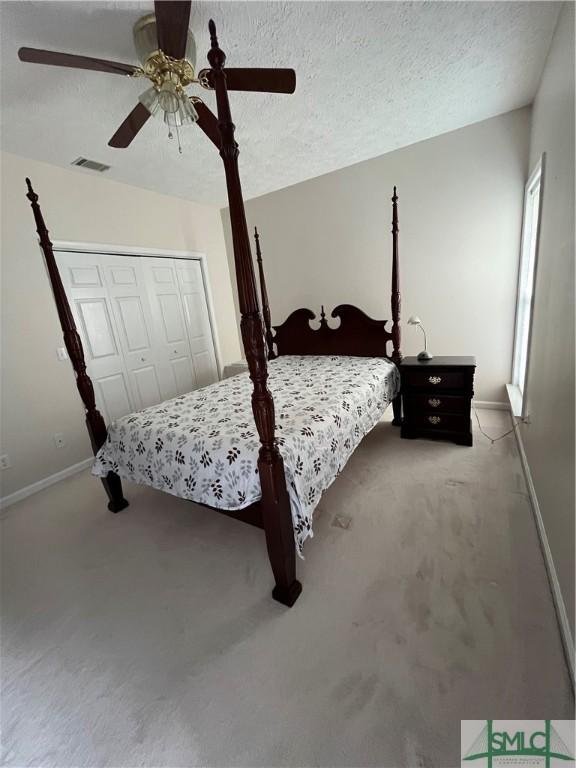 bedroom featuring ceiling fan, carpet, a textured ceiling, and a closet