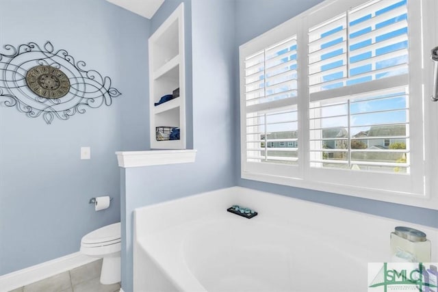 bathroom with tile patterned flooring, toilet, a wealth of natural light, and a tub to relax in