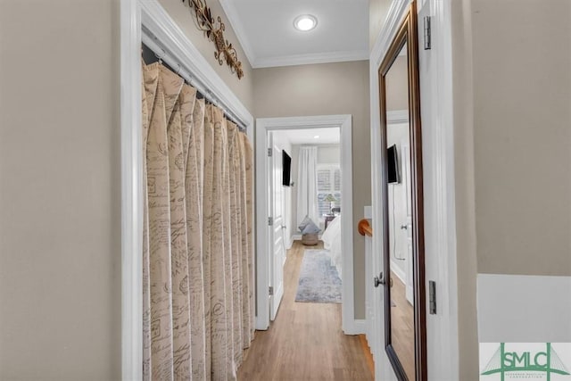 hallway with light hardwood / wood-style floors and crown molding