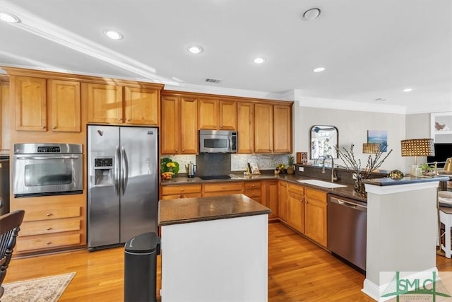 kitchen with sink, appliances with stainless steel finishes, crown molding, and light wood-type flooring