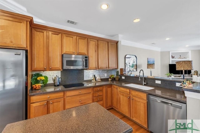 kitchen featuring appliances with stainless steel finishes, dark stone counters, crown molding, backsplash, and sink