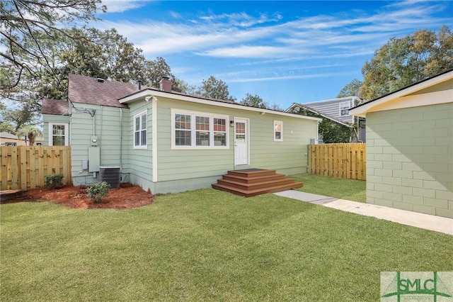 rear view of house featuring central AC unit and a lawn