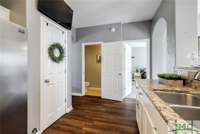 kitchen with white cabinetry, sink, dark hardwood / wood-style floors, and light stone counters