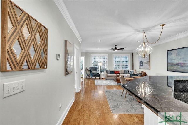 dining area featuring ceiling fan with notable chandelier, light wood-type flooring, and crown molding