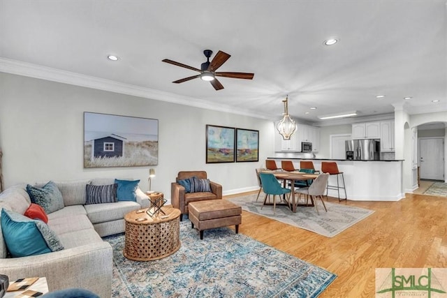 living room featuring light wood-type flooring, ornamental molding, and ceiling fan