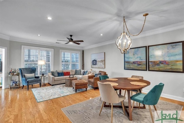 dining area featuring ornamental molding, hardwood / wood-style floors, and ceiling fan with notable chandelier