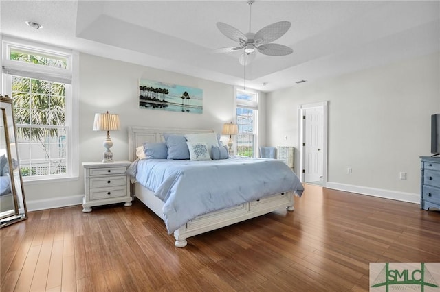 bedroom featuring hardwood / wood-style floors, ceiling fan, and a raised ceiling