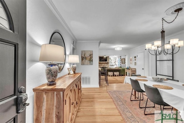 dining area featuring ornamental molding, light hardwood / wood-style floors, and a chandelier