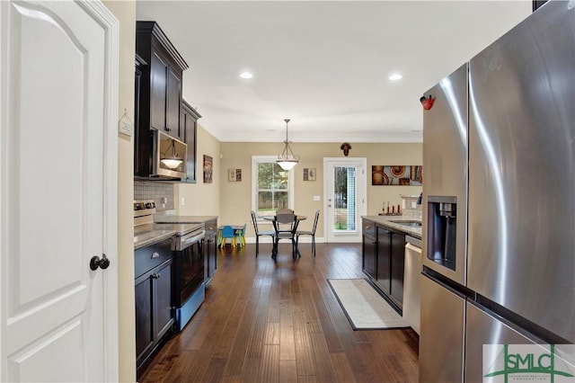 kitchen featuring tasteful backsplash, hanging light fixtures, dark wood-type flooring, stainless steel appliances, and ornamental molding