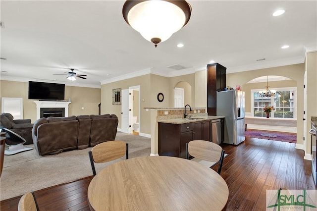 dining area featuring sink, ornamental molding, dark hardwood / wood-style flooring, and ceiling fan with notable chandelier