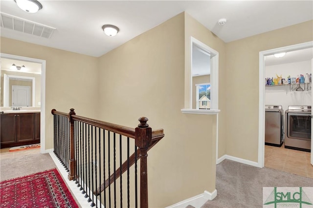 corridor featuring light carpet and independent washer and dryer