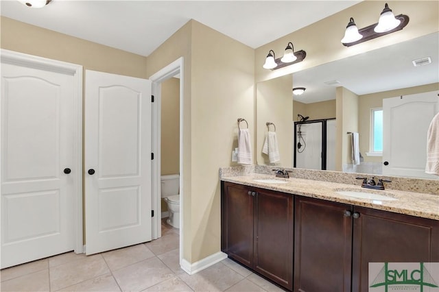 bathroom featuring tile patterned floors, vanity, toilet, and a shower with door