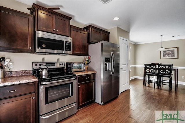 kitchen with dark brown cabinetry, stainless steel appliances, pendant lighting, and wood-type flooring