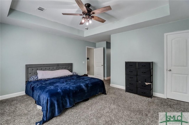 carpeted bedroom featuring a raised ceiling and ceiling fan