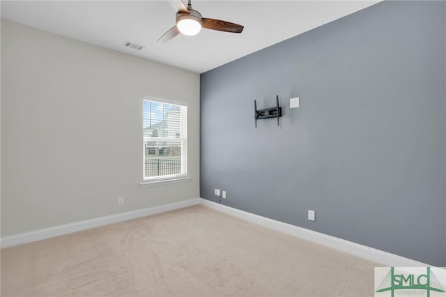 empty room with a ceiling fan, light colored carpet, visible vents, and baseboards