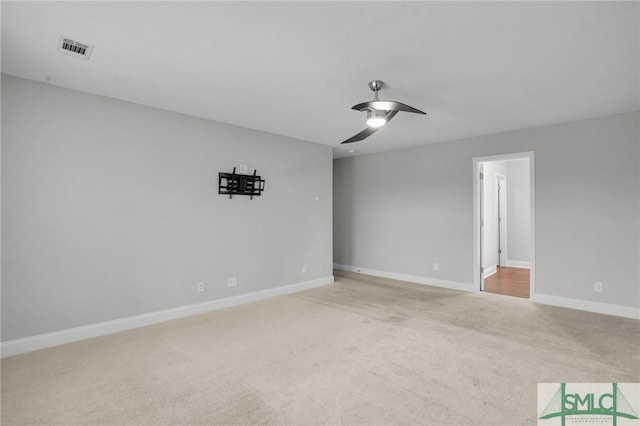 spare room featuring light carpet, ceiling fan, visible vents, and baseboards