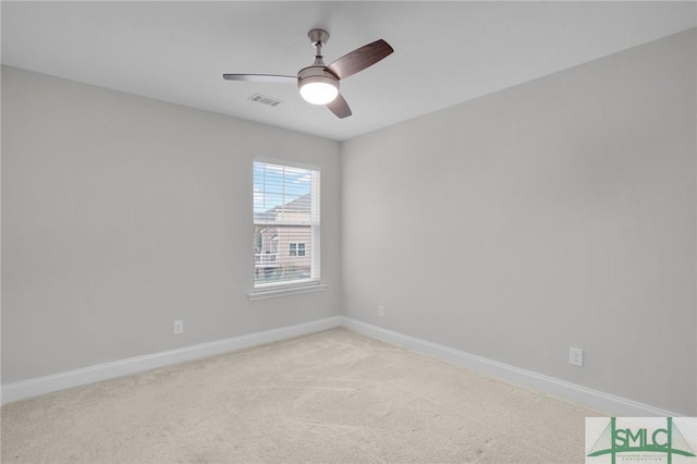 spare room with light colored carpet, visible vents, ceiling fan, and baseboards