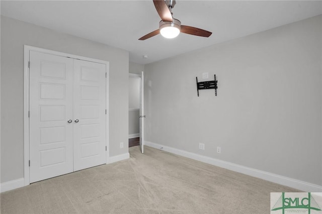 unfurnished bedroom featuring ceiling fan, baseboards, a closet, and light colored carpet