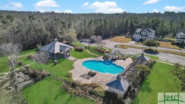 view of swimming pool with a patio, a water slide, a gazebo, a fenced in pool, and a wooded view