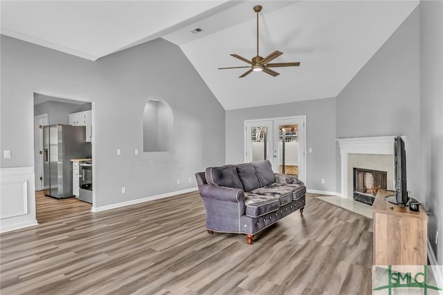 living room with light wood-type flooring, french doors, a premium fireplace, and ceiling fan