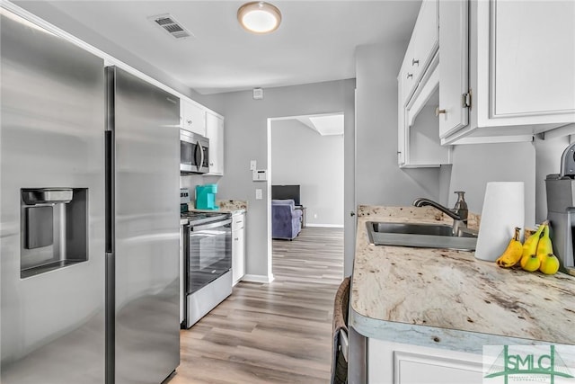 kitchen featuring appliances with stainless steel finishes, sink, white cabinetry, and light hardwood / wood-style floors