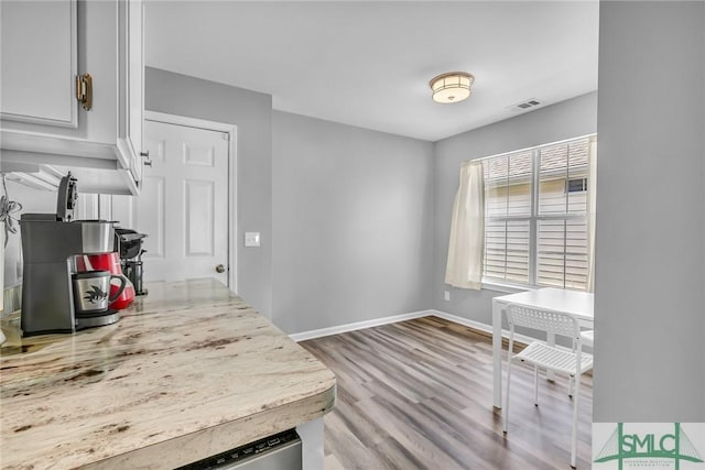 interior space with light wood-type flooring, white cabinets, and light stone counters