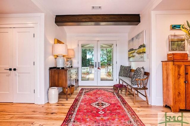 doorway featuring light wood-type flooring, french doors, and beamed ceiling