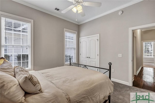 bedroom featuring ceiling fan, a closet, crown molding, and dark colored carpet