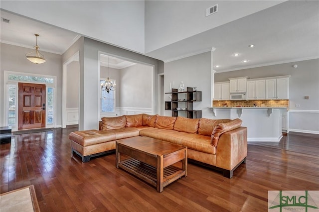 living room featuring dark hardwood / wood-style flooring, ornamental molding, and a chandelier