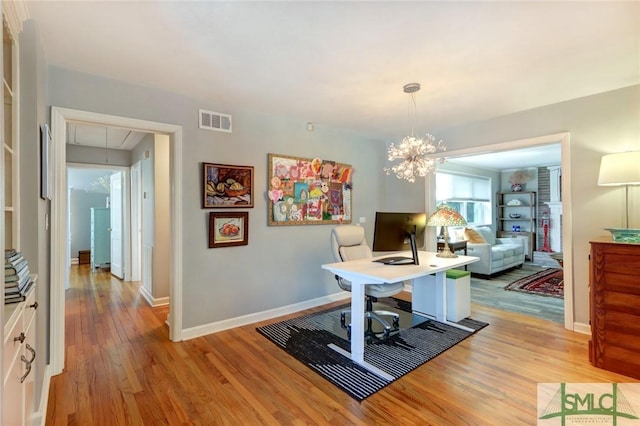 home office featuring light hardwood / wood-style floors and a notable chandelier