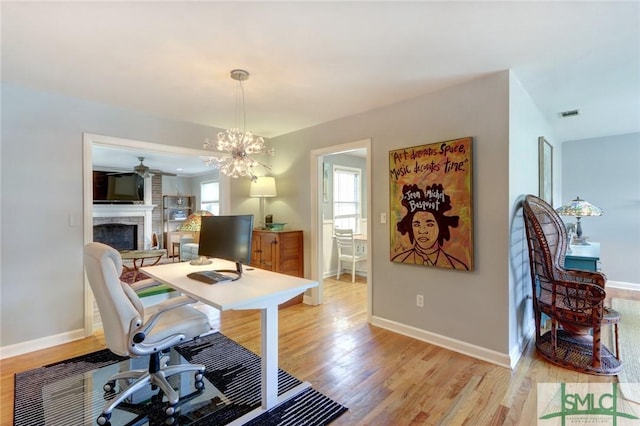 office with light wood-type flooring and an inviting chandelier