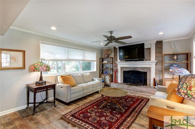 living room featuring a brick fireplace, light wood-type flooring, and ornamental molding