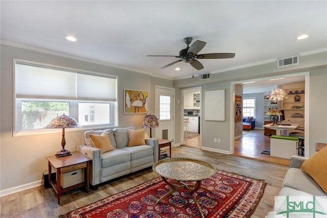 living room featuring wood-type flooring, ceiling fan, and crown molding