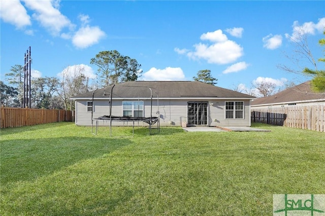 rear view of house with a yard, a trampoline, and a patio area