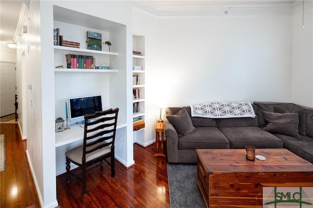 living room with ornamental molding, built in desk, dark hardwood / wood-style floors, and built in shelves