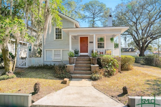 tri-level home featuring fence, a chimney, and covered porch