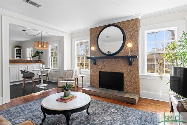 living area featuring crown molding, visible vents, a wealth of natural light, and dark wood-type flooring